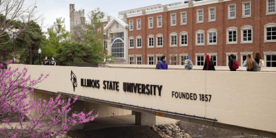 Puente sobre una calle y delante de un edificio de ladrillos mostrando el nombre Illinois State University.