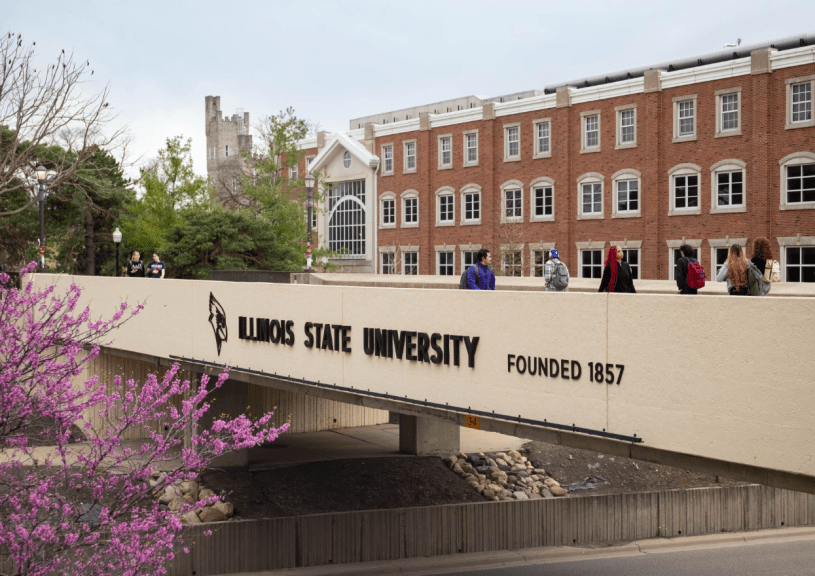 Puente sobre una calle y delante de un edificio de ladrillos mostrando el nombre Illinois State University.