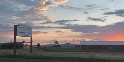 Un letrero que dice "Granja de ISU, Lexington", un campo abierto con un granero.