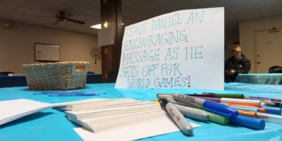 Letrero sobre una mesa con marcadores al lado, pidiendo a la gente que dejen un mensaje motivador para el atleta. Foto cortesia de WJBC