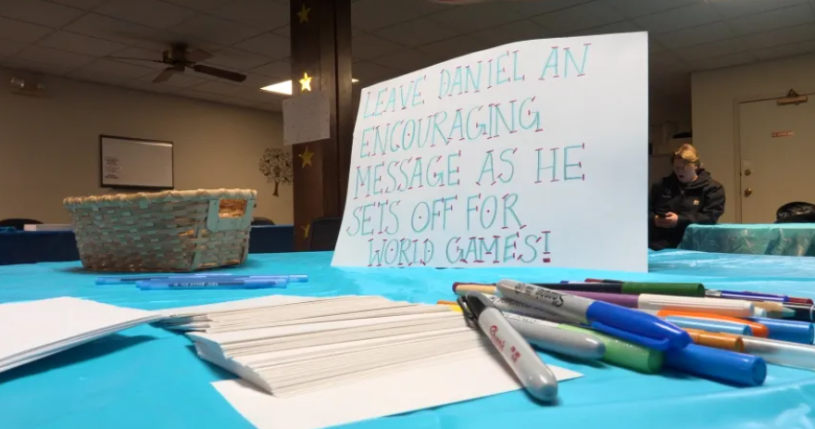 Letrero sobre una mesa con marcadores al lado, pidiendo a la gente que dejen un mensaje motivador para el atleta. Foto cortesia de WJBC