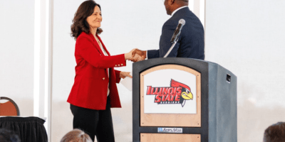 Nueva directora dando la mano al rector presidente de ISU.