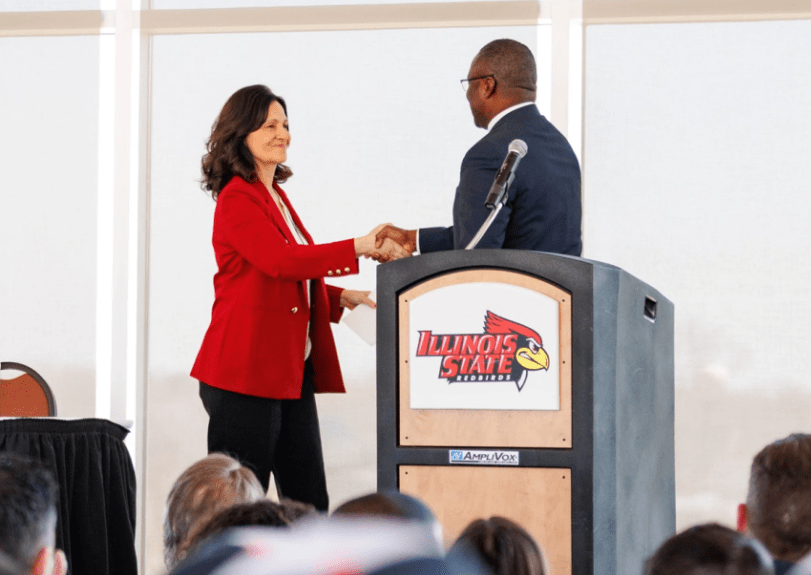 Nueva directora dando la mano al rector presidente de ISU.