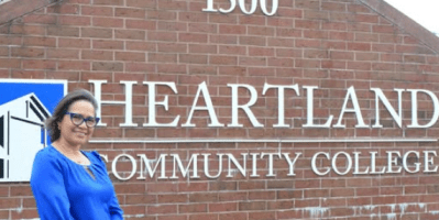 Una mujer en frente del letrero princiapl que identifica a HCC.