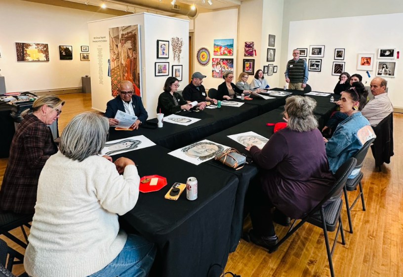 Varias personas sentadas alrededor de una mesa rectangular.