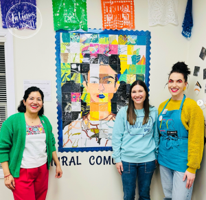 3 mujeres, las organizadoras, posando frente al mural comunitario.