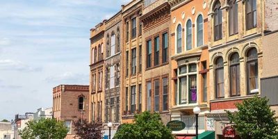 Una calle con edificios viejos y autos estacionados en el frente.