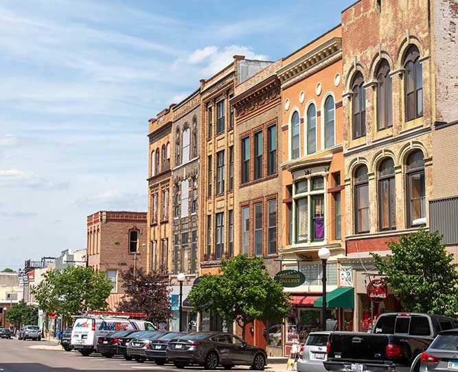 Una calle con edificios viejos y autos estacionados en el frente.