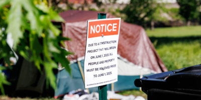Letrero frente a una tienda de campaña indicando que deben desalojar el espacio.