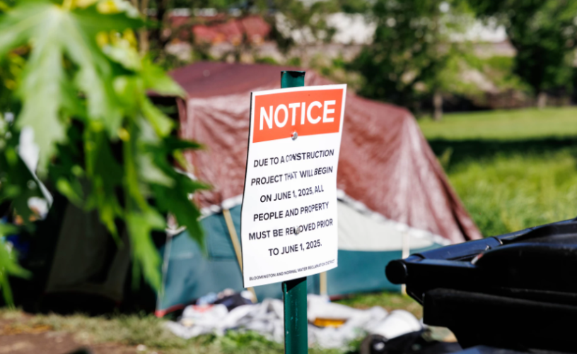 Letrero frente a una tienda de campaña indicando que deben desalojar el espacio.