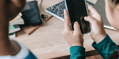 Dos niños en un escritorio usando un celular.