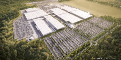 Vista aérea de la planta de Rivian en Georgia, con grandes naves industriales, estacionamientos y bosque alrededor.