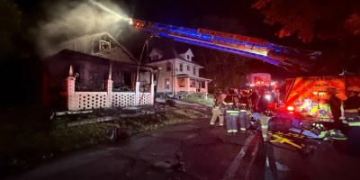 Bomberos operando el camión que tira agua sobre la casa medio destrozada.