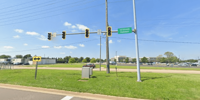 Señal de tránsito de Veterans Parkway en Bloomington-Normal con tráfico vehicular.