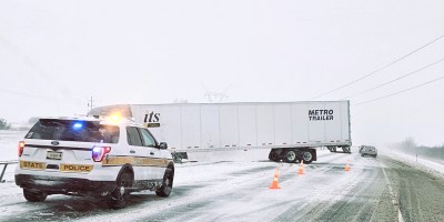 Camion accidentado en la carretera y un carro de la policia estatal parado al lado.