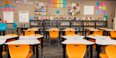 Salón de clase con sillas y mesas, sin estudiantes.