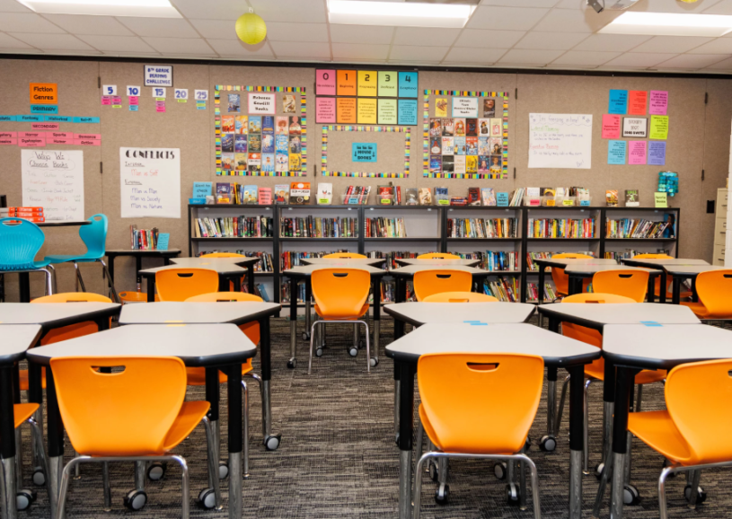 Salón de clase con sillas y mesas, sin estudiantes.