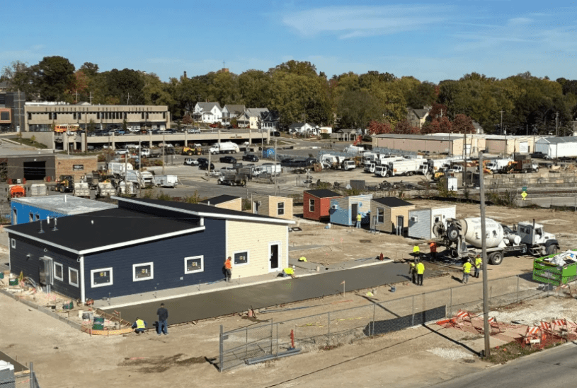 Vista de las cabinas individuales del albergue The Bridge en construcción, con voluntarios pintando las estructuras.