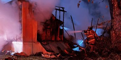 Bomberos de Normal combatiendo el incendio de una casa tráiler durante la madrugada.