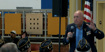 Grupo de veteranos y miembros de la comunidad reunidos en Heartland Community College durante una ceremonia por el Día de los Veteranos.