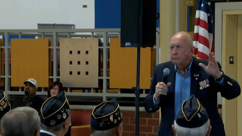 Grupo de veteranos y miembros de la comunidad reunidos en Heartland Community College durante una ceremonia por el Día de los Veteranos.