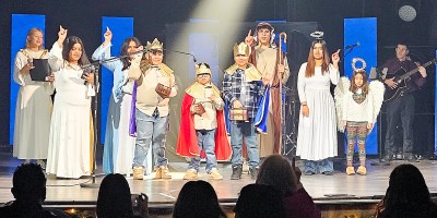 Niños vestidos con disfraces sobre el escenario, representando el nacimiento de Jesús.