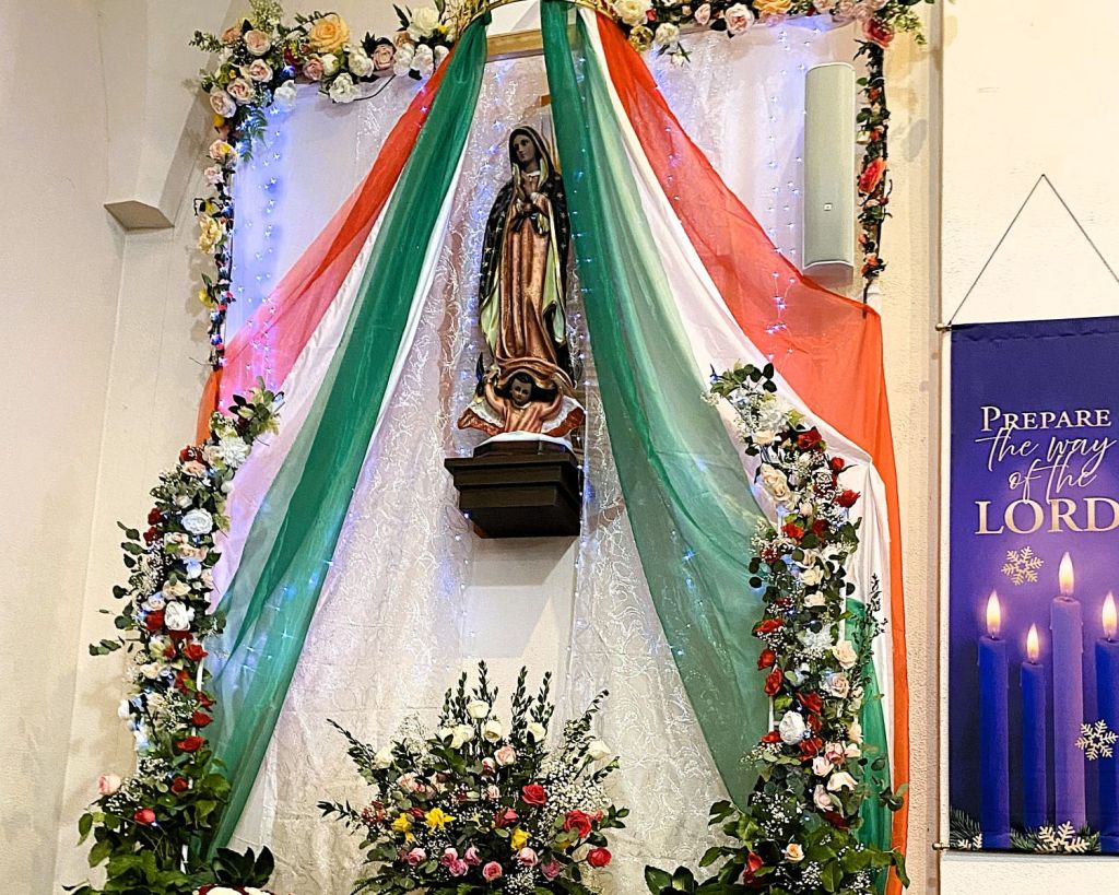 Altar de la iglesia católica St. Mary’s en Bloomington durante la celebración del Día de la Virgen de Guadalupe, decorado con flores, veladoras y la imagen de la Virgen.
