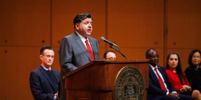 gobernador JB Pritzker hablando en un podium durante su visita a ISU.