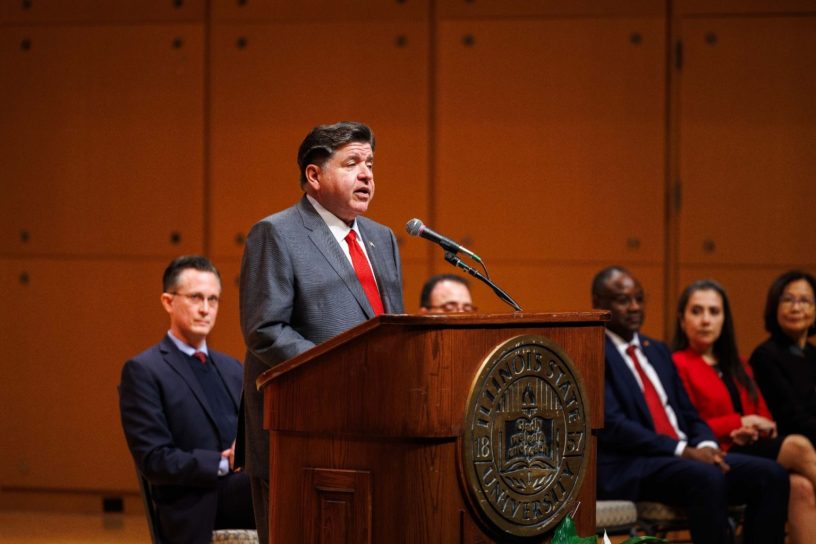 gobernador JB Pritzker hablando en un podium durante su visita a ISU.