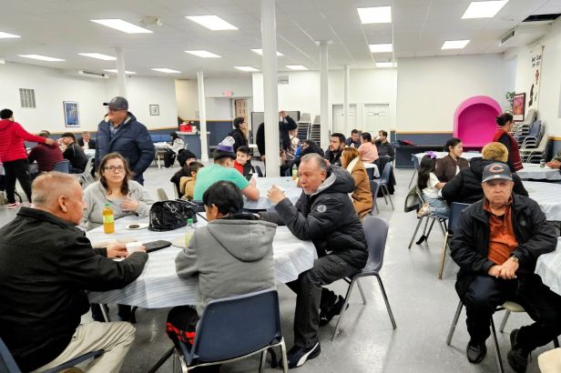Un salon con mesas redondas y gente sentada alrededor