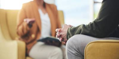 Man, hands and listening for therapy, sofa or advice from woman for mental health, psychology or care. Psychiatrist, patient and frustrated in clinic, session or couch for help, anxiety or depression.