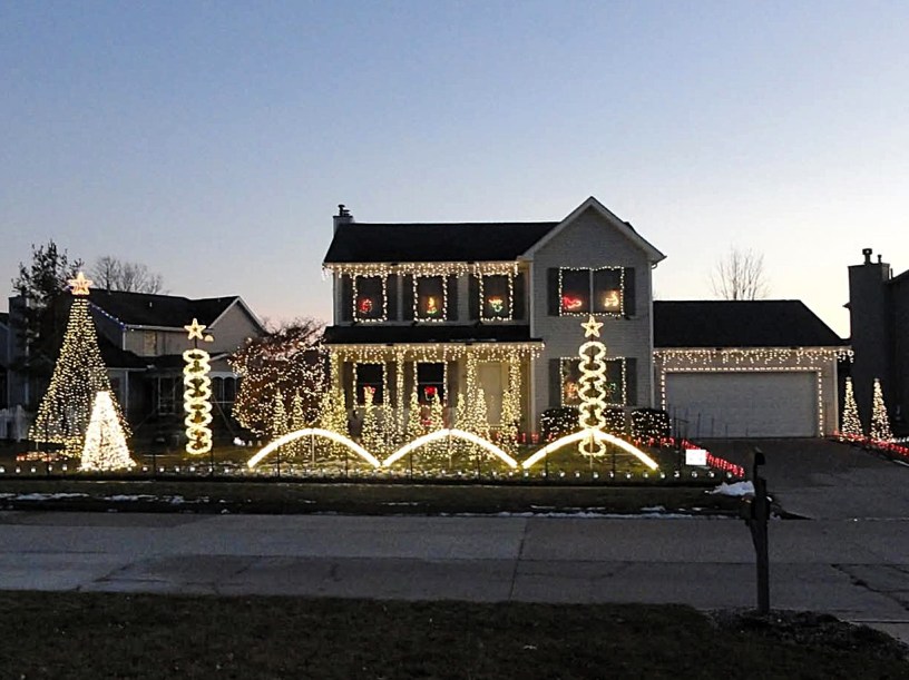 Fachada de una casa en Bloomington decorada con miles de luces navideñas sincronizadas con música, encendidas de noche durante un espectáculo comunitario.