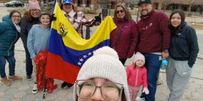 Venezolanos reunidos en Uptown Normal celebrando la salida de Nicolás Maduro, con banderas y sonrisas.