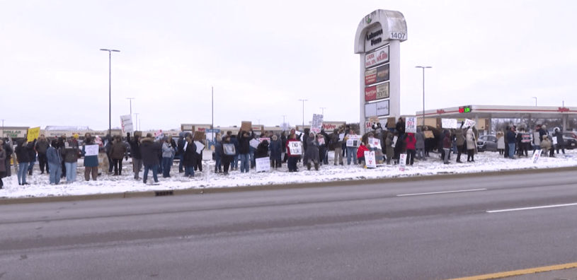 Personas con pancartas protestan pacíficamente contra ICE a lo largo de Veterans Parkway en Bloomington.