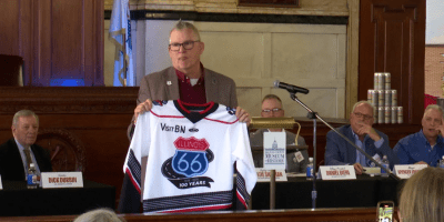 Un hombre sostiene la camiseta de los Bison de Bloomington conmemorativa al centenario de la ruta 66.